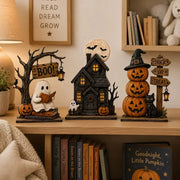 Halloween ghost, haunted house, and pumpkin figurines glowing on a bookshelf
