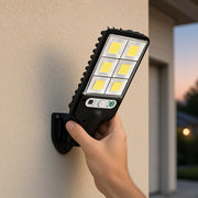 Installing compact solar security light on garage wall — real hand scale